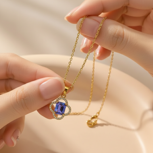 Gold necklace with a iridescent gemstone pendant held by hands showing the beautiful details. 
