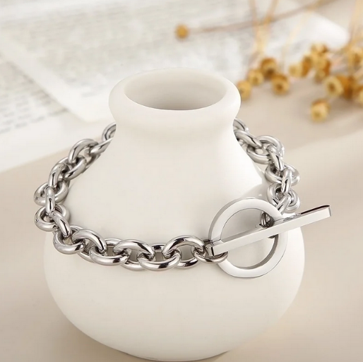 Silver chain bracelet secured with a distinctive toggle clasp, which consist of a circular ring on one end and a bar on the other, that is passed through the ring to fasten the bracelet.
