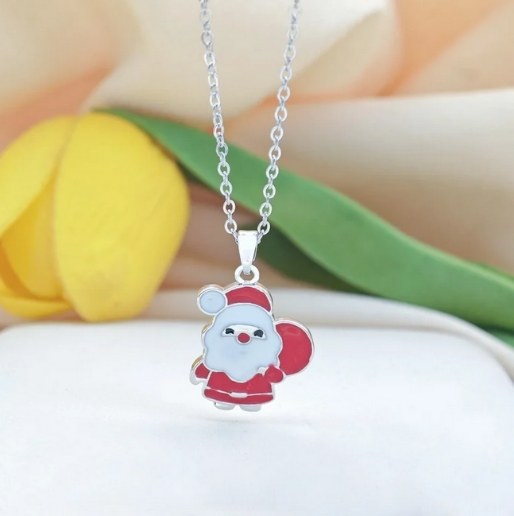 Charming necklace featuring a Santa Claus pendant in his classic red and white attire, rendered with vibrant enamel detailing, and it is suspended from a delicate silver toned chain.