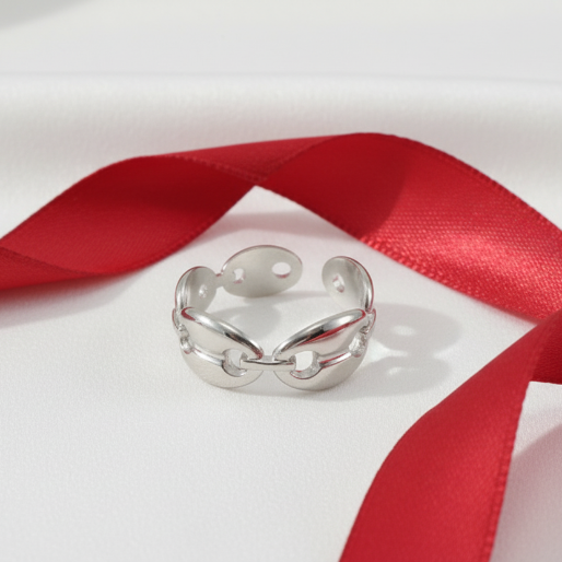 Silver open mariner ring on a light gray background, contrasting with a red ribbon