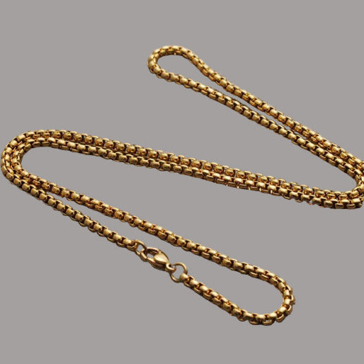 Gold chain necklace on a textured gray fabric background