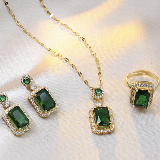 Gold Jewelry set with green gemstones on a white background