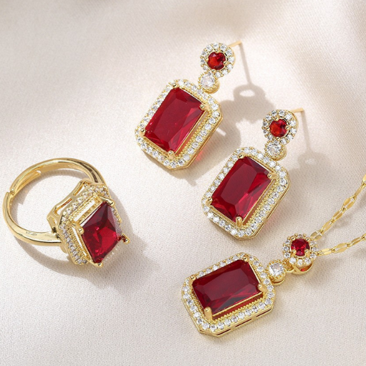 Gold jewelry set with red gemstones on a light background
