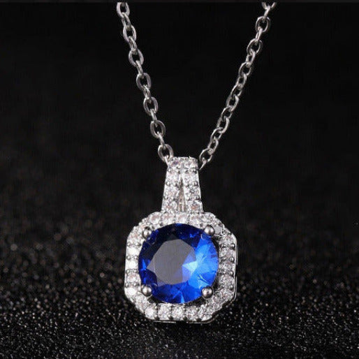 Silver necklace with a blue gemstone pendant on a black background