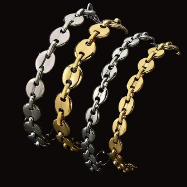 Two gold and silver mariner chain bracelets on a dark textured surface