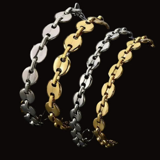Two gold and silver mariner chain bracelets on a dark textured surface