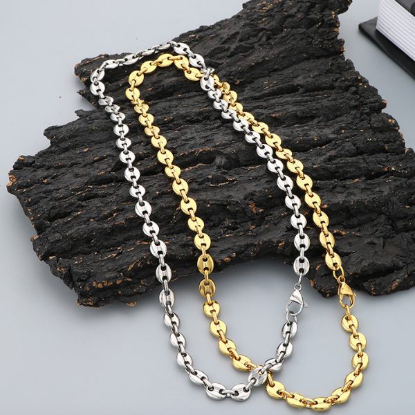 Two Gucci Puff Chain necklaces, one gold and one silver, on a wooden surface.