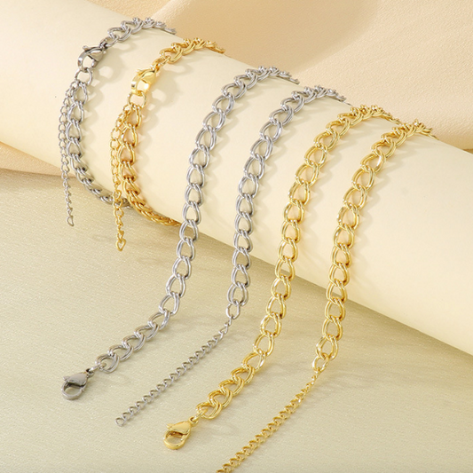 Gold and silver chain and bracelet sets on a beige fabric background