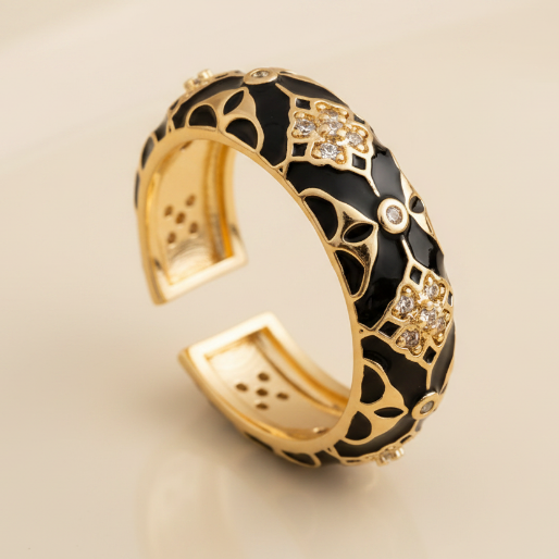 Gold and black enamel ring with zircon accents on a textured background