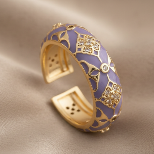 Gold and purple enamel ring with floral designs on a textured surface