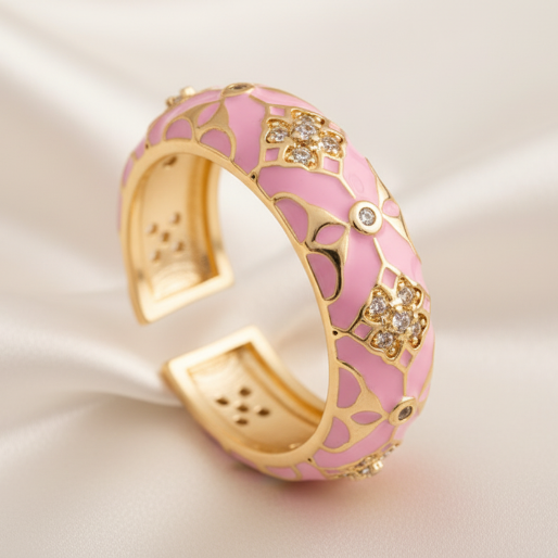 Gold and pink enamel ring with floral design on a white textured background