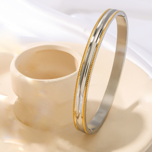 One dual tone bracelet on a light beige surface with a soft focus background