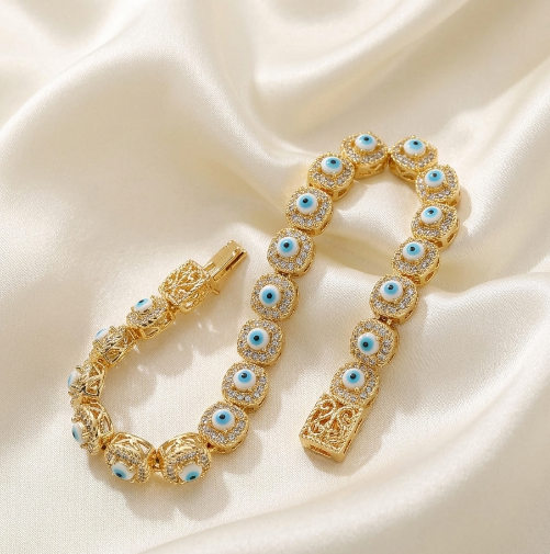 Gold bracelet with blue evil eye gemstones on a beige fabric background