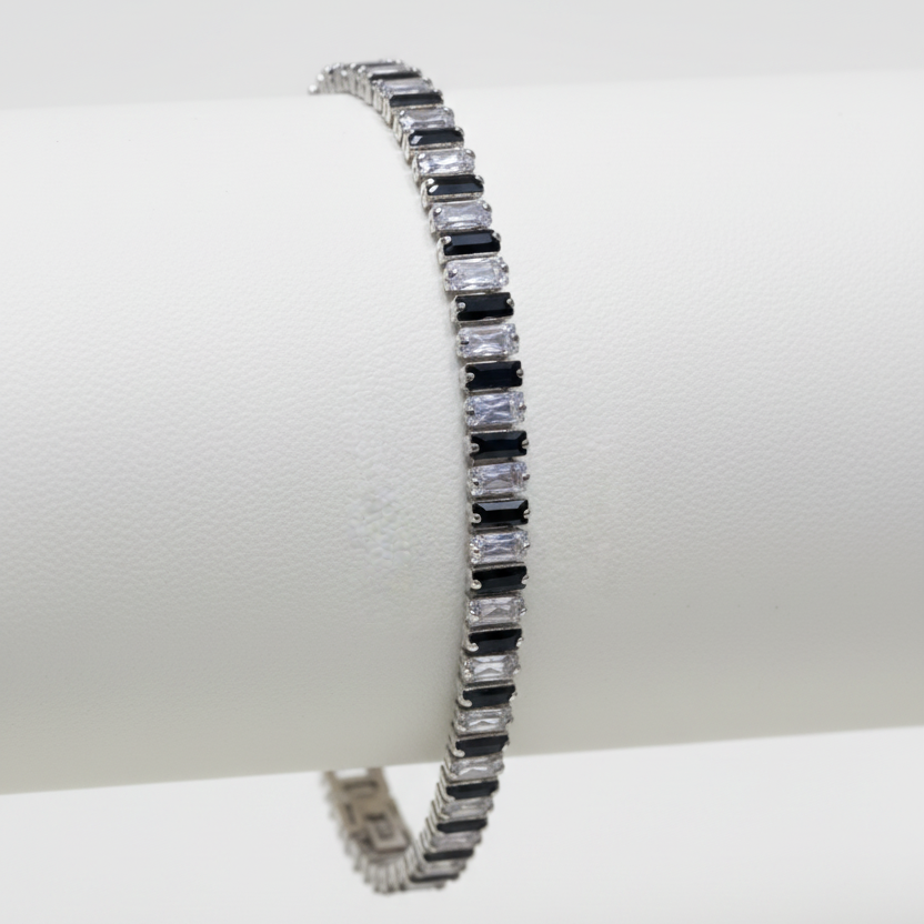 Silver bracelet with black and clear gemstones on a white background