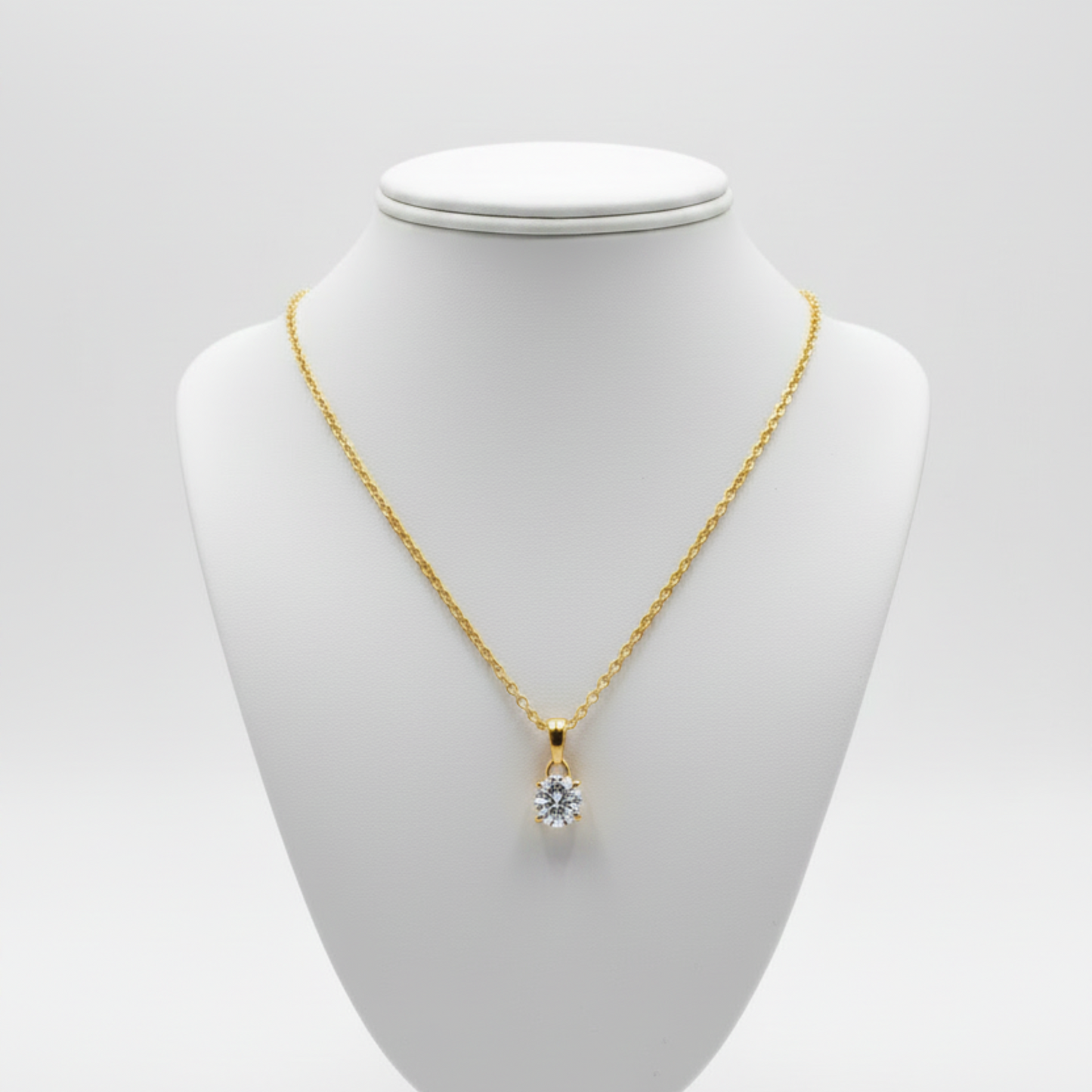 Gold necklace with a clear moissanite gemstone pendant on a white background