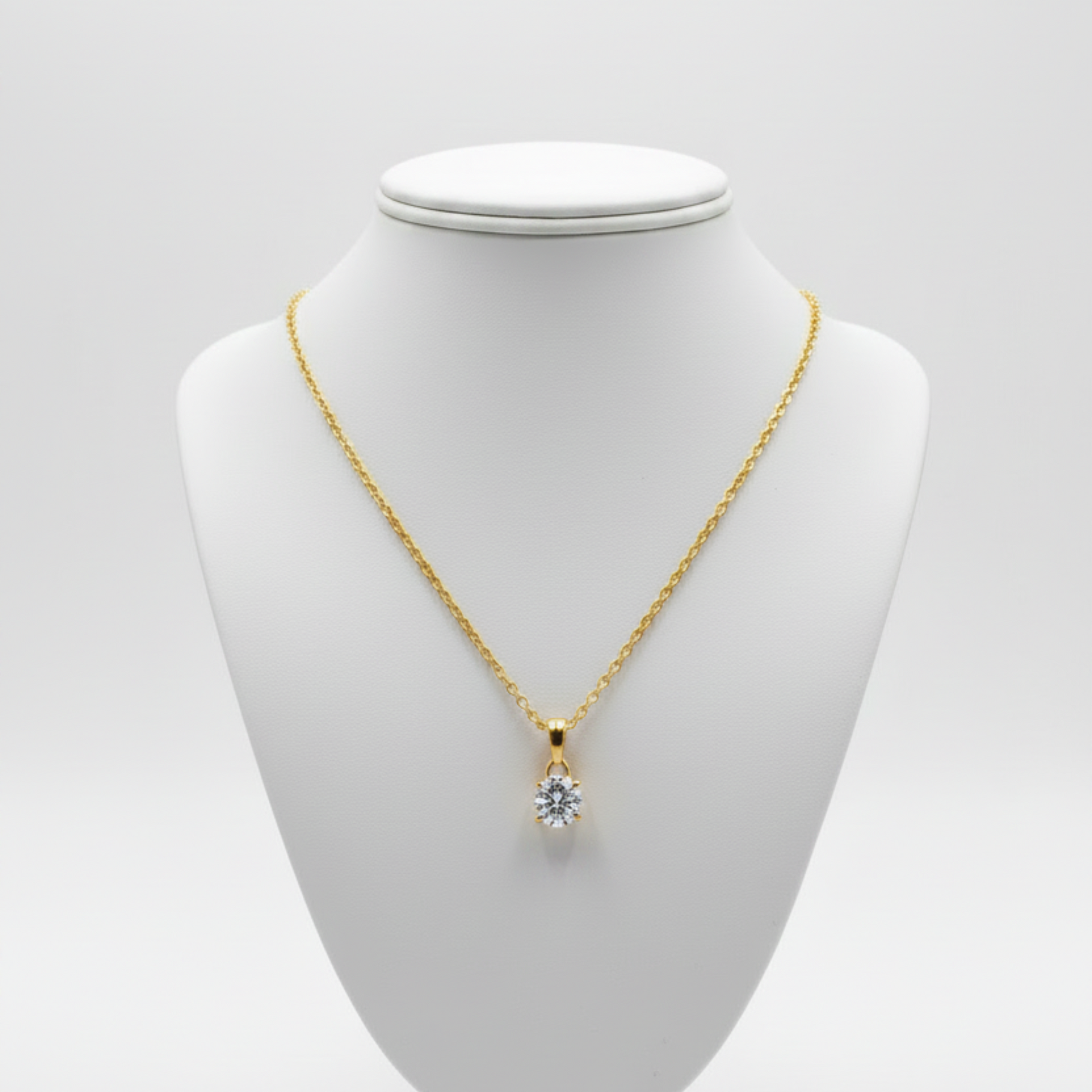 Gold necklace with a clear moissanite gemstone pendant on a white background