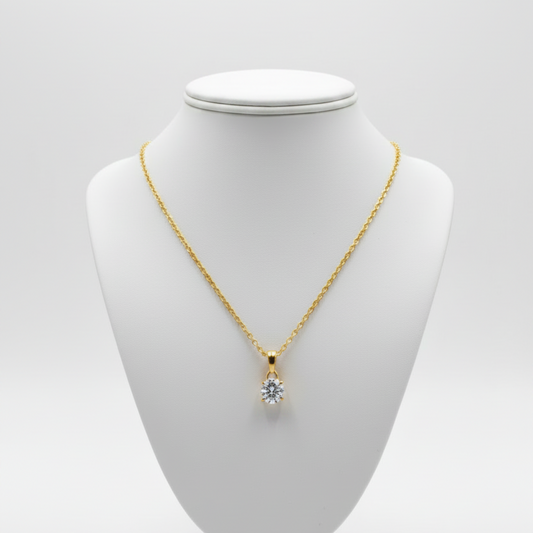 Gold necklace with a clear moissanite gemstone pendant on a white background