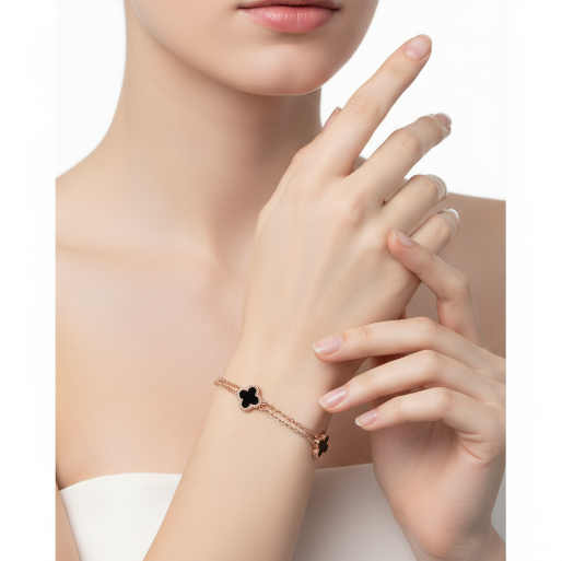 Close-up of a hand wearing a delicate bracelet with three black clover charm and a double chain in rose gold finish. 
