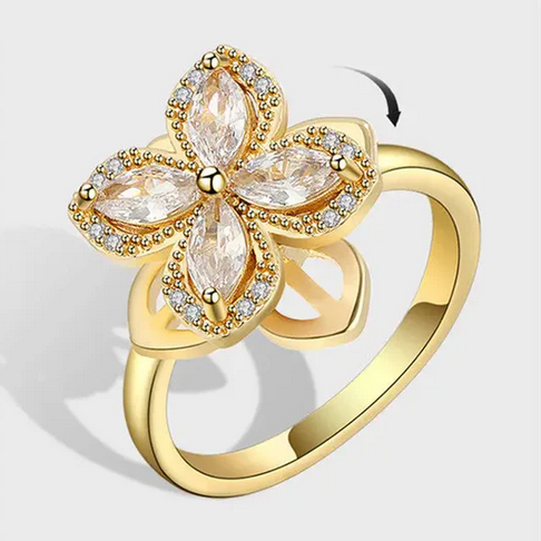 Gold flower fidget spinner ring, with a centerpiece consisting of four petals, each set with a marquise-cut clear stone, and surrounded by smaller pave-set clear stones, giving a sparking appearance.