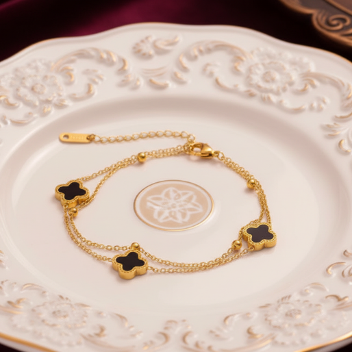 Gold bracelet with black clover-shaped charms on a white plate