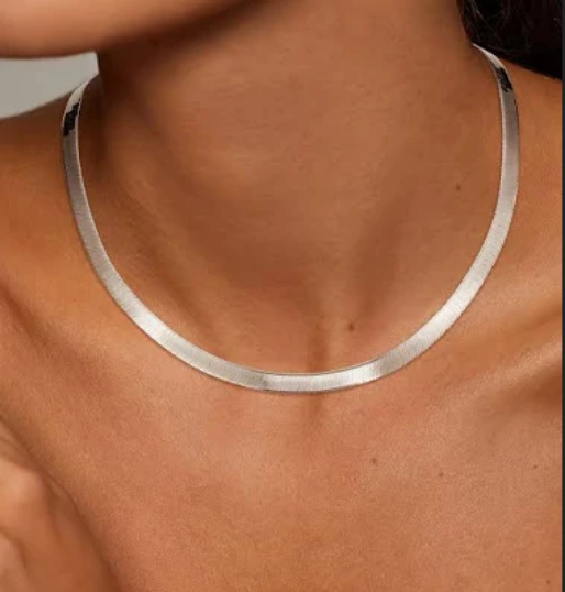 Silver herringbone necklace on a person's neck with a neutral background
