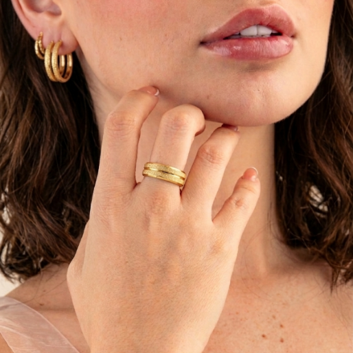 Close-up of a person wearing a textured gold band ring.