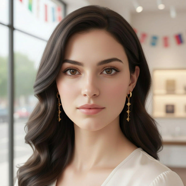 Woman with long dark hair wearing gold stellar triad dangle earrings. The stars feature etched lines, enhancing their radiant appearance.